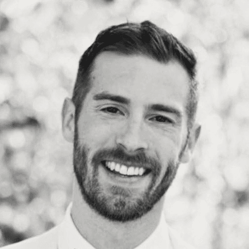 Brandon George, smiling, in a white shirt, outdoors.