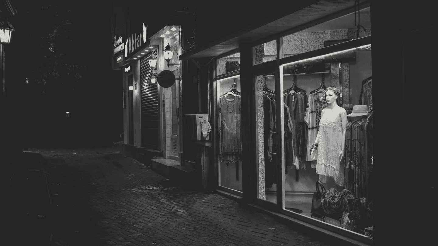 A lit shop window on a dark street at night.